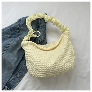 Vue détaillée de la texture gaufrée jaune clair et du nœud sur le sac à bandoulière demi-lune
