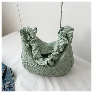 Détail du sac dumpling vert clair présentant une texture gaufrée et un tissu matelassé