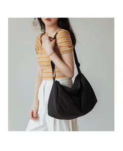 Détail d'un grand sac bandoulière noir en tissu plissé avec bandoulière réglable
