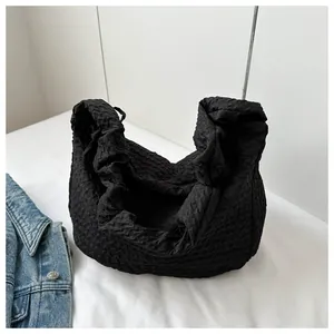 Détail du tissu noir à texture popcorn sur un sac à bandoulière minimaliste décontracté