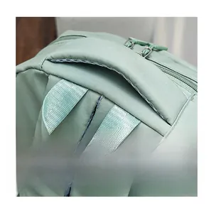Detail view of thickened top handle and durable zipper on light green nylon backpack