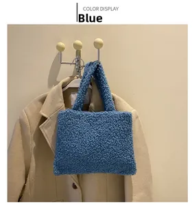Blue fuzzy fleece tote bag displayed against a beige coat for a stylish winter look
