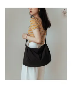 Grand sac bandoulière en toile noire avec texture plissée douce et forme demi-lune sur modèle