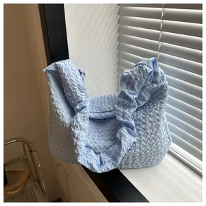 Gros plan sur la texture gaufrée bleu clair d'un sac à bandoulière souple et chic