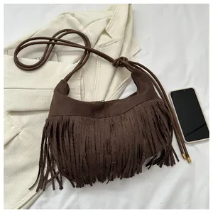 Close-up of brown suede crossbody bag with long tassels and refined metal hardware