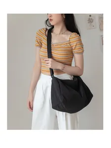 Femme portant un grand sac bandoulière minimaliste en toile noire dans un cadre moderne