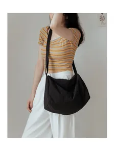 Gros plan d'un grand sac bandoulière noir en toile avec sangle réglable porté par un mannequin