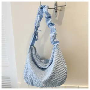 Détail du sac hobo bleu clair avec bandoulière à volants et tissu à texture gaufrée