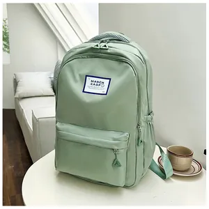 Detail view of mint green nylon backpack with front zipper pocket on a white table