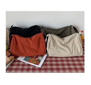 Détail de quatre sacs bandoulière en nylon de couleurs variées sur une nappe à carreaux