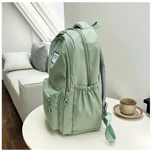 Detail of sage green nylon backpack featuring multi-layer zip pockets and brand label