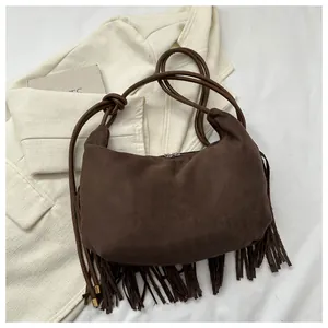 Detail of dark brown suede hobo bag featuring long fringe tassels and a zipper closure