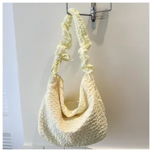 Détail du sac à bandoulière jaune clair à texture popcorn avec bandoulière à volants et nœud