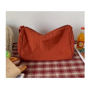 Détail d'un sac bandoulière plissé rouge brique en nylon pour des scènes de pique-nique