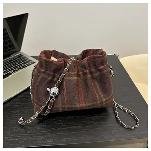 Détail du sac seau en laine à carreaux avec bandoulière chaîne et bille en métal