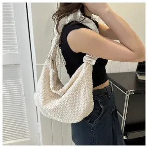 Détail du sac à bandoulière crème avec texture à bulles et design de bandoulière nouée