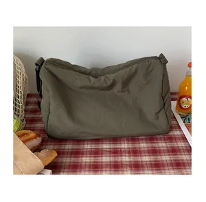 Détail d'un sac bandoulière en nylon vert olive avec plis et large bandoulière réglable