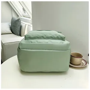 Side view of light green casual backpack on a white table in a cozy indoor setting