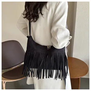 Detail of black suede shoulder bag featuring long tassels and gold metal zipper closure