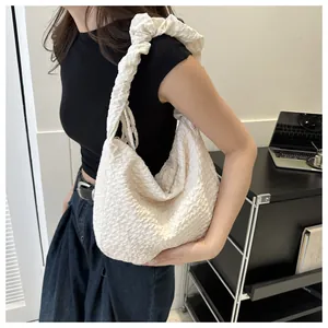Détail du sac à bandoulière blanc à texture popcorn avec bandoulières plissées minimalistes