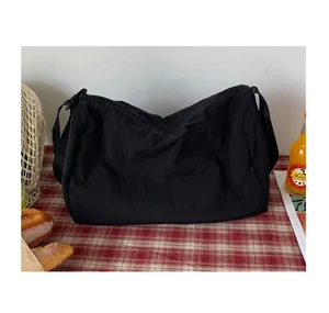 Détail du sac fourre-tout en nylon noir plissé sur une table avec des accessoires