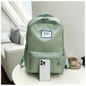Detail of mint green school backpack featuring a front zipper pocket and white brand label