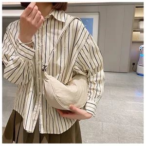 Detail van beige nylon halve maan tas gedragen crossbody met verstelbare riem en textuur