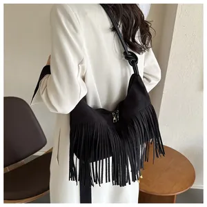 Detail of black suede crossbody bag featuring long tassels and knotted leather shoulder strap