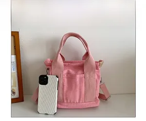 Confronto dimensioni borsa tote in tela rosa con smartphone e dettagli della tracolla