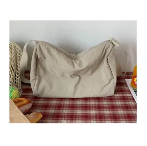 Gros plan d'un sac cabas plissé beige sur une nappe à carreaux rouges style pique-nique