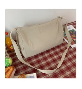 Détail du sac bandoulière en nylon plissé beige sur une nappe de pique-nique à carreaux