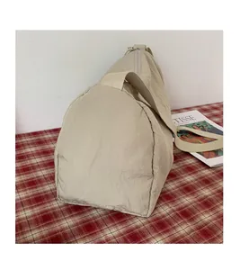 Détail de la texture plissée du sac de voyage en nylon beige avec bandoulière solide