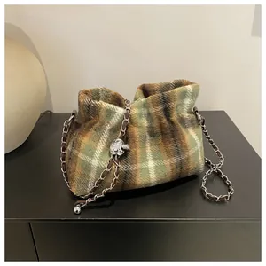 Détail du sac à carreaux en laine avec motif vert et bandoulière en chaîne