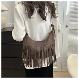 Detail of dark brown suede half-moon bag with long tassels and elegant knot shoulder strap