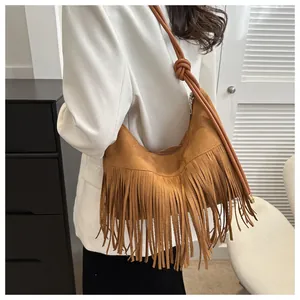 Detail of a brown suede hobo bag with fringe tassels and knot design on shoulder strap