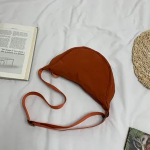 Detail van minimalistische nylon halve maan tas in steenrood met schouderband