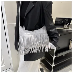 Detail of light gray suede crescent bag featuring long tassels and double zipper closure