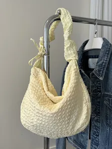 Sac à bandoulière jaune clair avec texture plissée et nœud sur un cintre