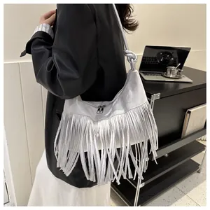 Close-up of grey suede crossbody bag featuring long stylish tassels and knotted strap details