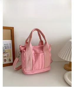 Dettaglio della borsa in tela rosa con manici robusti e tracolla rimovibile regolabile