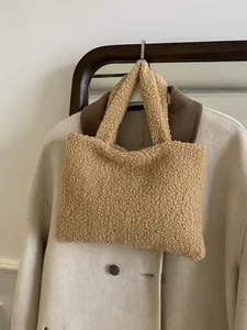Minimalist plush fleece tote bag in camel beige displayed against a cashmere coat
