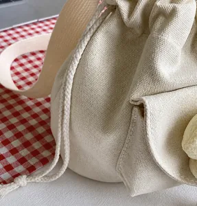 Detail view of thick woven drawstring rope and durable canvas texture on mini bucket bag
