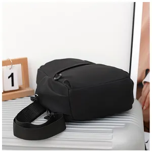Detail of black nylon sling bag on silver suitcase showing durable fabric and adjustable strap