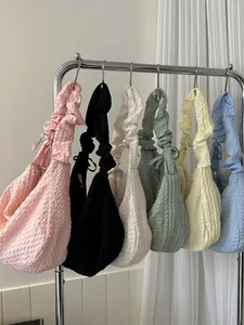 Sacs à bandoulière texturés en six couleurs suspendus sur un support minimaliste