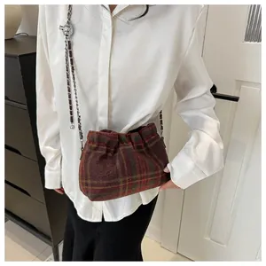 Détail du sac seau à carreaux rouge et vert avec plis texturés et bandoulière chaîne
