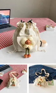 Detail of white canvas bucket bag featuring a 3D yellow plush flower and drawstring