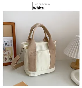 Borsa tote in tela bianca con manici marroni e tracolla rimovibile su un tavolo bianco