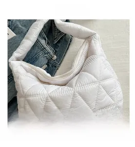 Close-up of white quilted puffer bag featuring a diamond stitch pattern and secure zipper