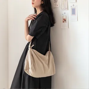 Grand sac à bandoulière en toile beige minimaliste présenté dans un décor de style de vie