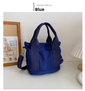 Dettaglio della borsa in tela blu con tracolla rimovibile in un ambiente minimalista